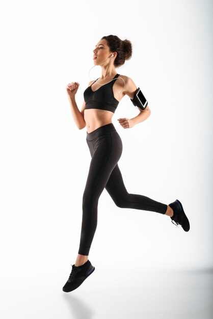 Young curly brunette fitness woman running and listening music