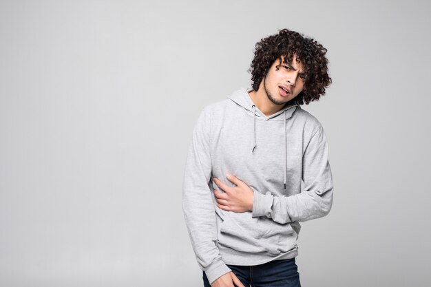 Young curly handsome man suffering pain due to sedentary lifestyle isolated on white wall