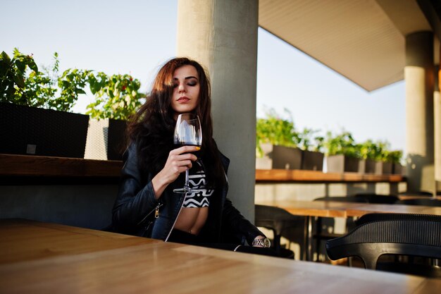 Young curly woman enjoying her wine in a bar