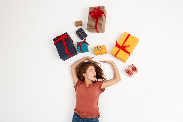 Foto gratuita giovane donna riccia che si trova fra i contenitori di regalo