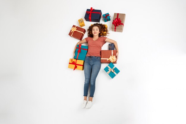 Young curly woman lying on floor among gift boxes