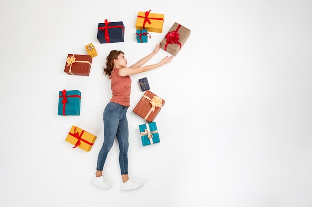 Young curly woman lying on floor among gift boxes