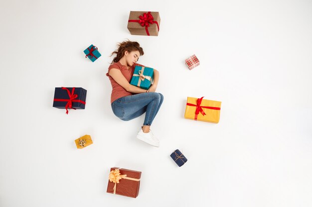 Young curly woman lying among gift boxes