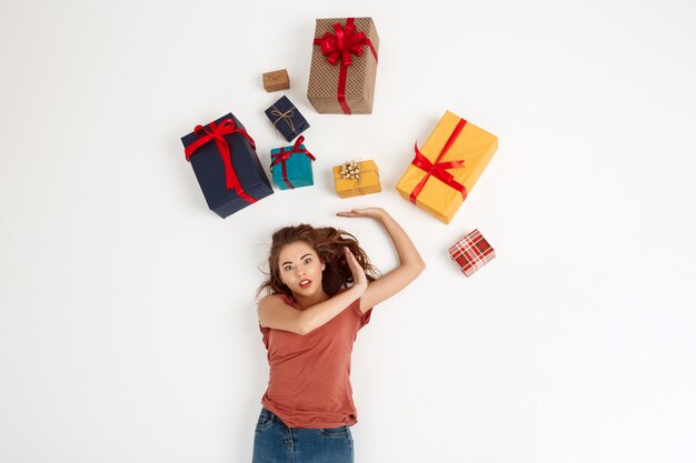 Young curly woman lying among gift boxes