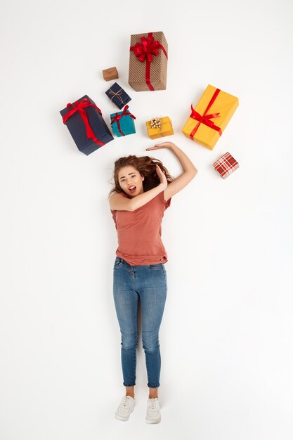 Young curly woman lying among gift boxes