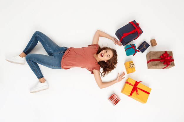 Young curly woman lying among gift boxes