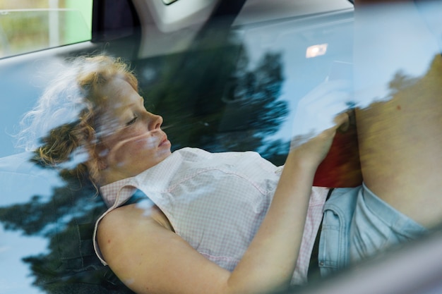 Young curly woman resting while lying in car