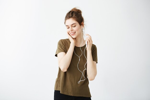 Young cute brunette woman smiling listening music in hedphones over white background.