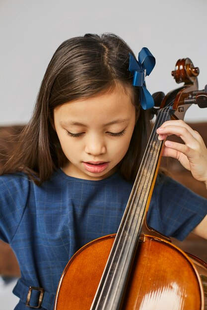 Молодая милая девушка учится играть на виолончели