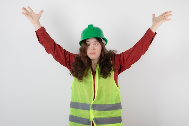 Giovane ragazza carina in piedi in maglia e in posa con le mani alzate.