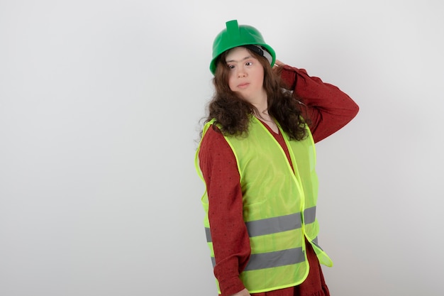 young cute girl with down syndrome standing in vest and holding crash helmets .