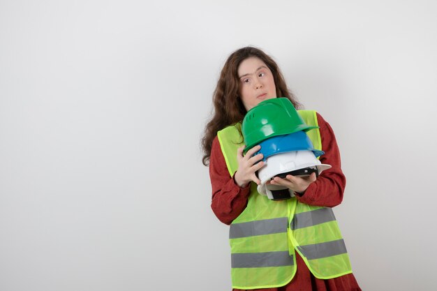 young cute girl with down syndrome standing in vest and holding crash helmets .