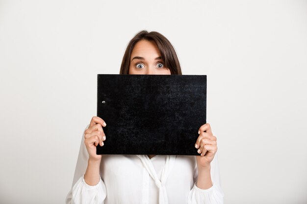 Young cute woman cover mouth with clipboard