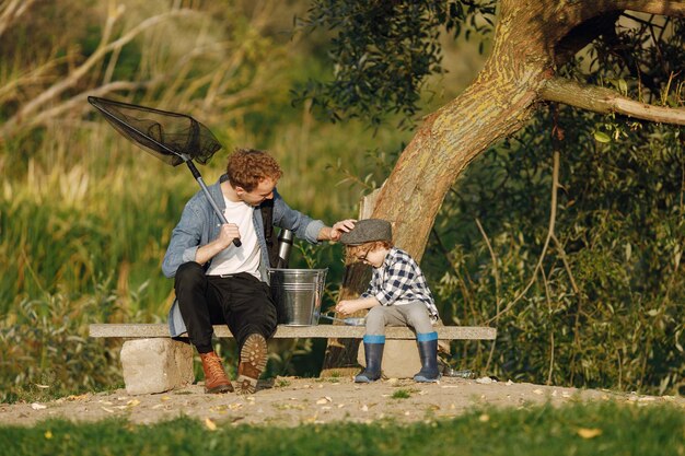 Young dad and his child boy spend time outdoors together. Curly toddler boy wearing a plaid shirt and a hat