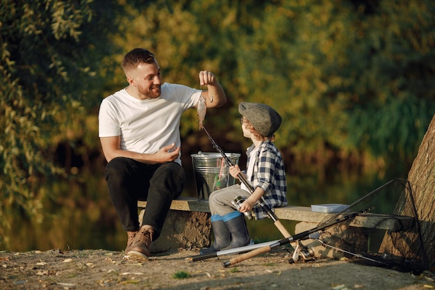 Young dad and his child boy spend time outdoors together. Curly toddler boy wearing a plaid shirt and a hat