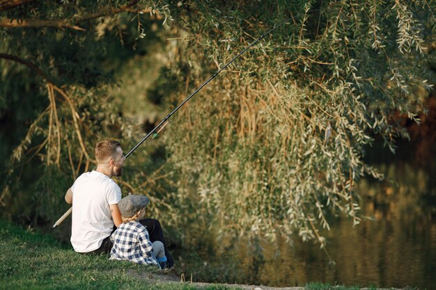 Young dad and his child boy spend time outdoors together. Curly toddler boy wearing a plaid shirt and a hat