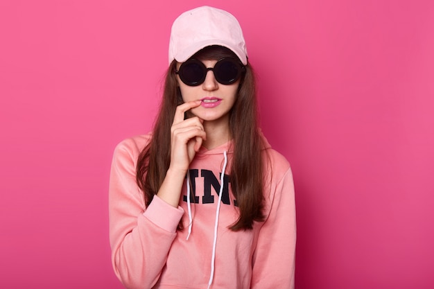 Молодая темноволосая девушка-подросток в стильной розовой толстовке
