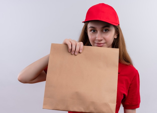 빨간색 유니폼 보여주는 종이 가방과 격리 된 흰 벽에 젊은 배달 소녀