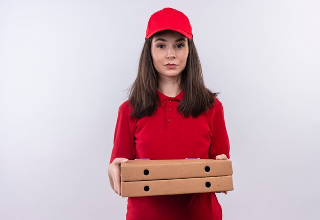 Молодая доставщица в красной футболке в красной кепке держит коробку для пиццы на изолированном белом фоне
