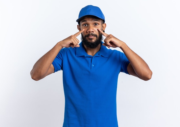 young delivery man putting fingers on eyelids isolated on white wall with copy space