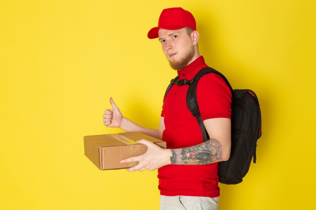 빨간색 폴로 빨간 모자 흰색 청바지와 노란색에 상자를 들고 검은 배낭에 젊은 배달 남자