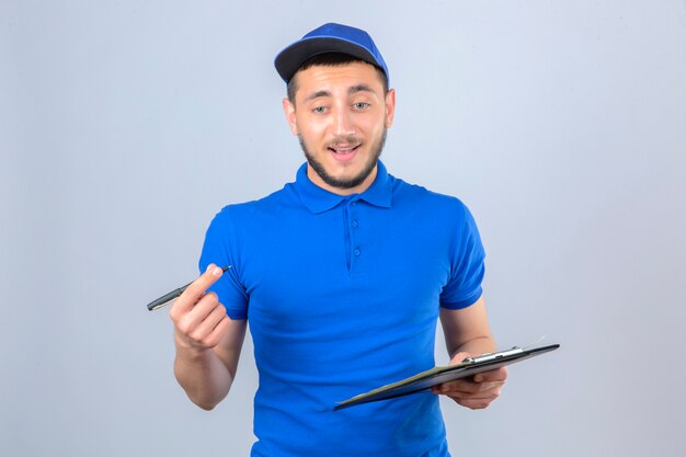 Young delivery man wearing blue polo shirt and cap standing with clipboard and pen over isolated white background