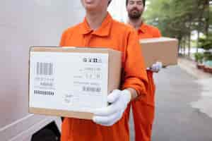 Free photo young delivery men moving boxes out of car