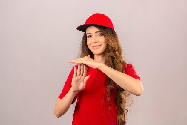 Young delivery woman wearing red polo shirt and cap smiling making time out gesture over isolated white background