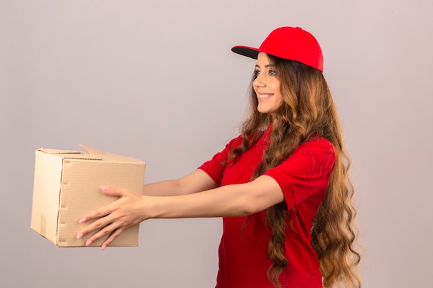 Young delivery woman wearing red polo shirt and cap young delivery woman wearing red polo shirt and cap giving cardboard box to customer with smile on face over isolated white background