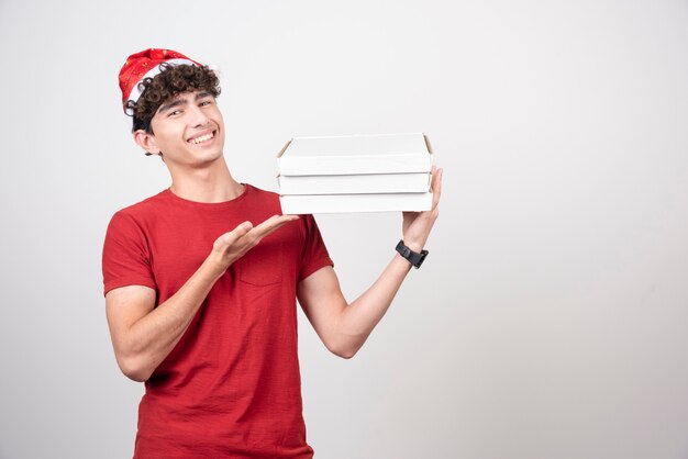 Young deliveryman showing off pizza boxes.