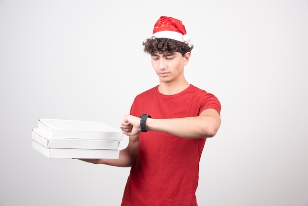 Young deliveryman with pizza boxes checking the time.