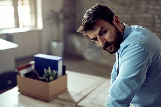 Free photo young displeased businessman thinking in the office after losing his job