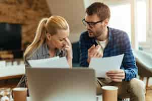 Free photo young displeased couple talking while analyzing their home finances