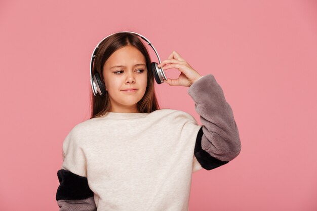 Young displeased girl push her headphones because of loudness