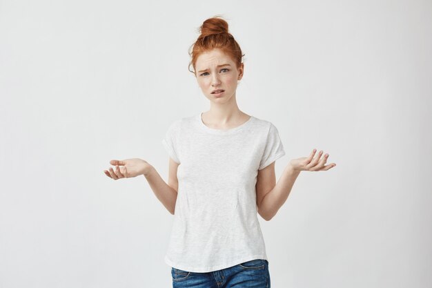 Young displeased redhead woman gesturing Confused woman arguing with a boyfriend. White.