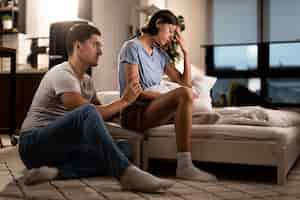 Free photo young displeased woman ignoring her boyfriend who is trying to apologize after a quarrel in the bedroom