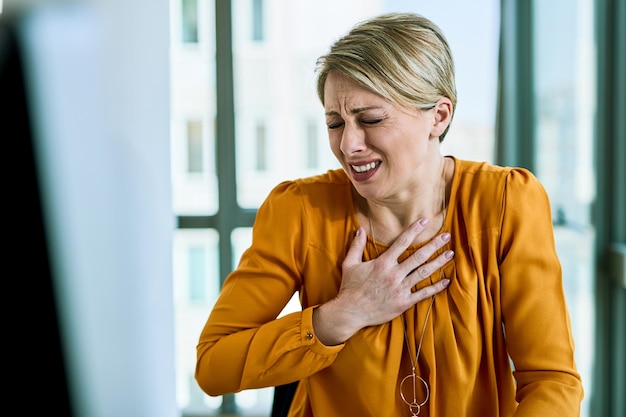 Young distraught businesswoman feeling chest pain while working in the office