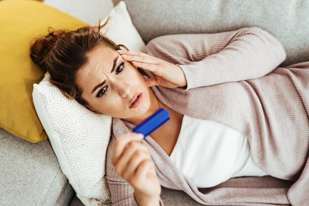 Young distraught woman waiting for pregnancy test outcome at home