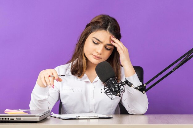 Young Dj is feeling tired Young girl sitting behind the desk on purple background High quality photo