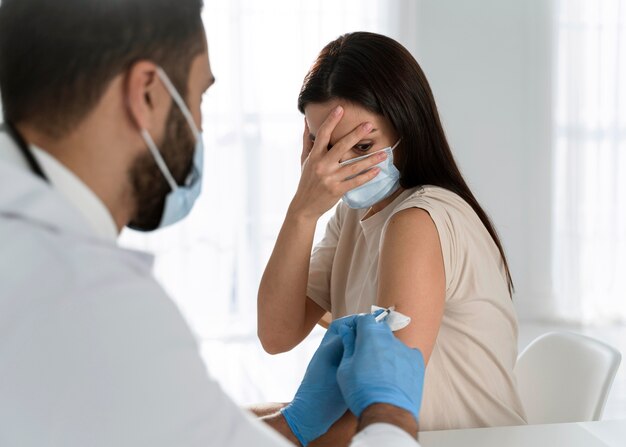 young doctor doing a vaccine to a frightened patient