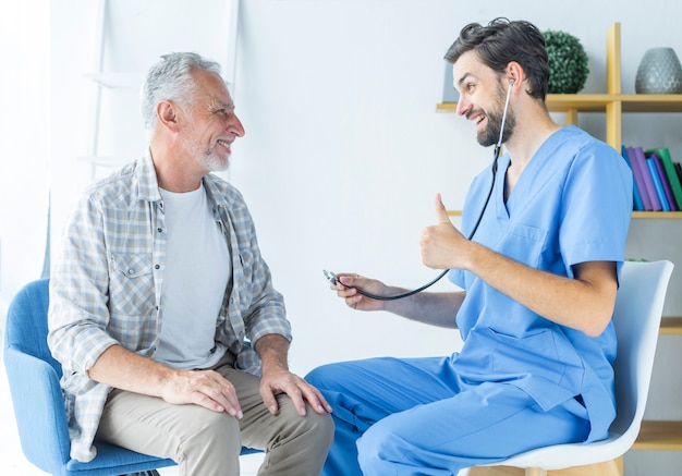 Young doctor gesturing thumb-up to elderly patient