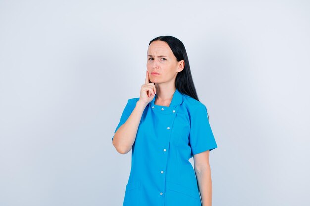 Young doctor is thinking by holding forefinger on cheek on white background