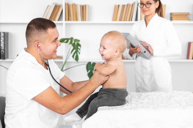 Young doctor listening adorable baby with stethoscope