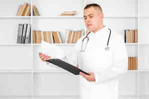 Free photo young doctor looking on sheets from a clipboard