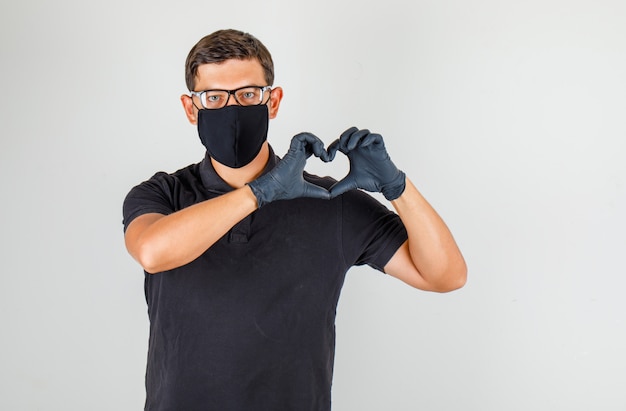 Young doctor making heart gesture in black polo shirt and looking glad