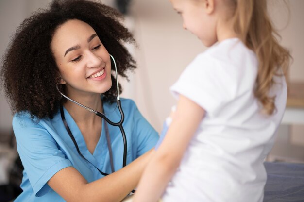 Молодой врач проверяет, что с маленькой девочкой все в порядке после вакцинации