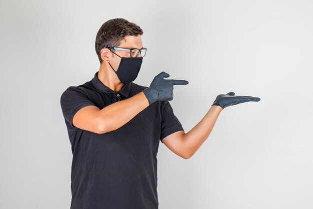 Young doctor pointing fingers towards right in black polo shirt