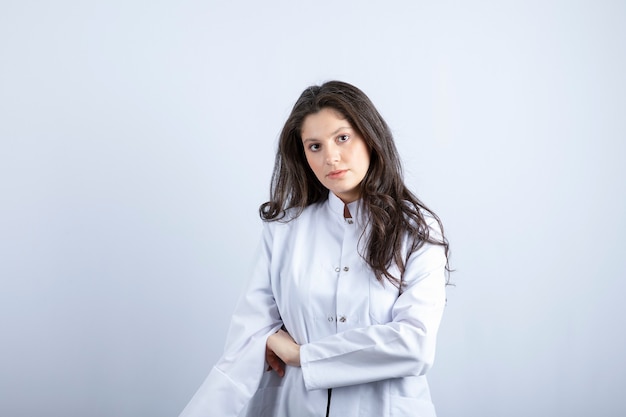 young doctor posing and standing on white wall.