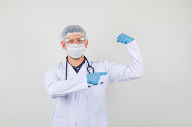 Young doctor showing his muscle in white coat, hat, gloves and looking strong and independent