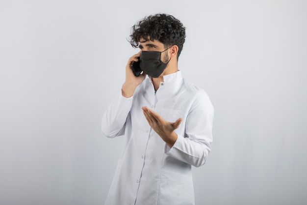 Young doctor talking phone and wearing mask.